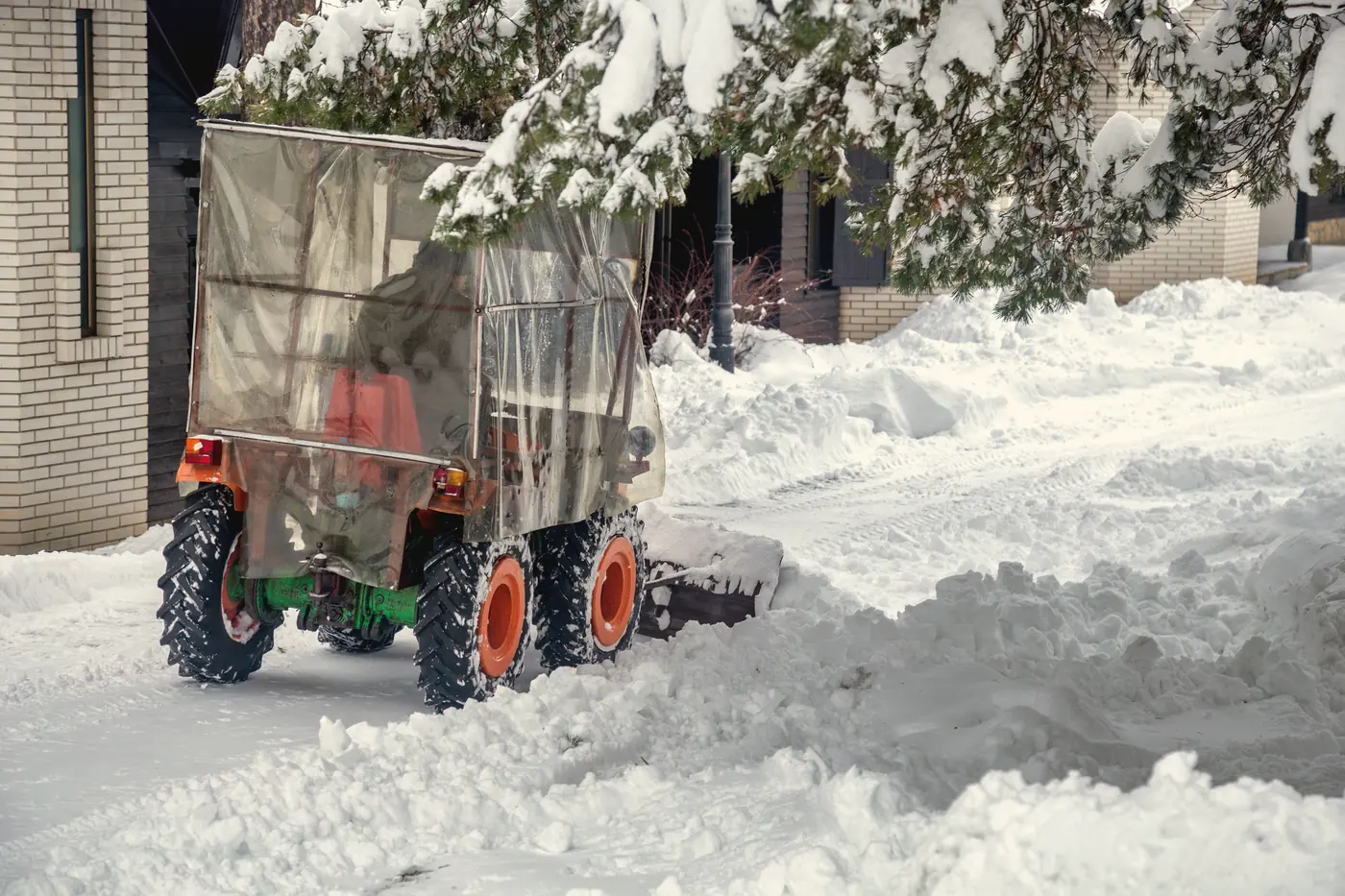 Tracteur à souffleuse déneigeant une entrée résidentielle