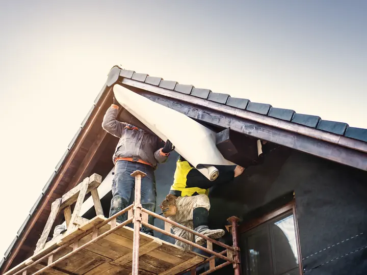 Ouvriers refaisant la toiture d'une maison depuis un échafaud
